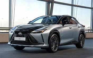 Lexus RZ prateado com capô preto, visto de frente e de lado em um salão.